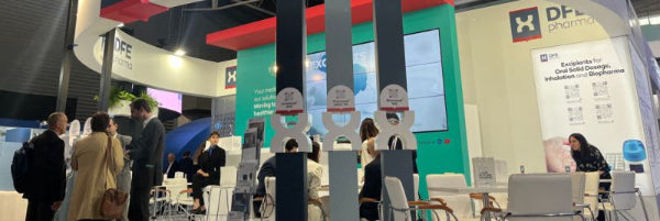 DFE Pharma booth at a trade show with people asking questions